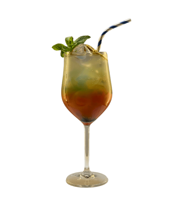 A colorful tropical cocktail served in a tall glass with a straw and mint garnish.