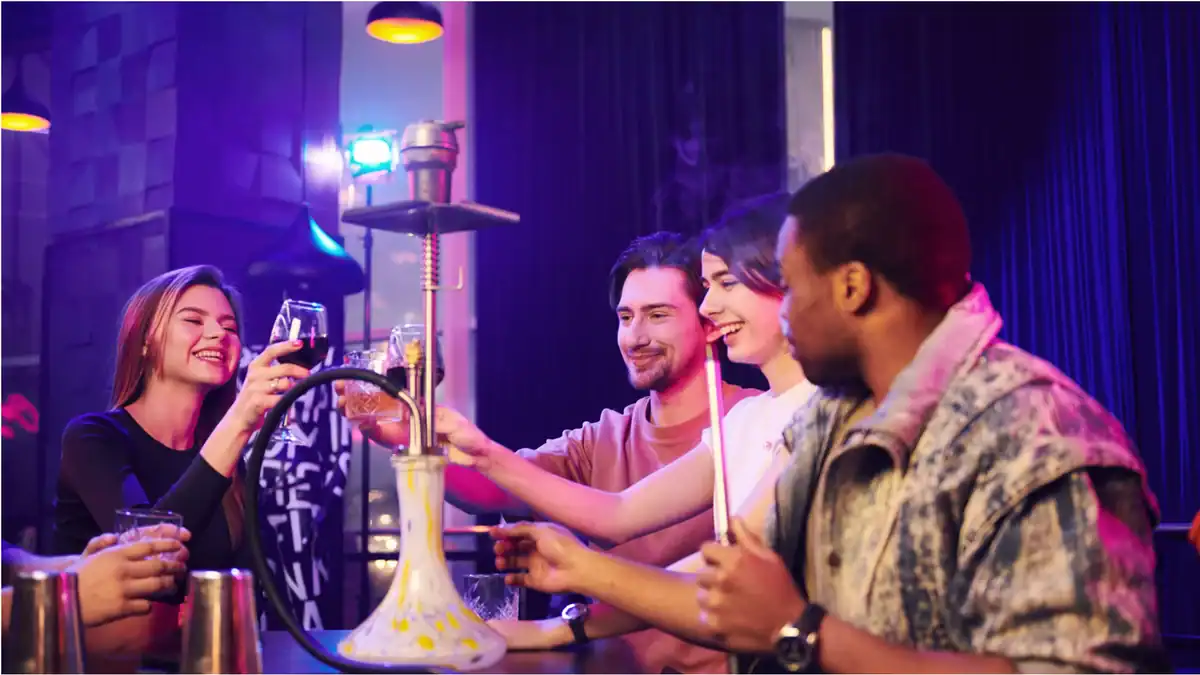 Group of friends enjoying shisha at Nijmegen lounge with colorful lighting.